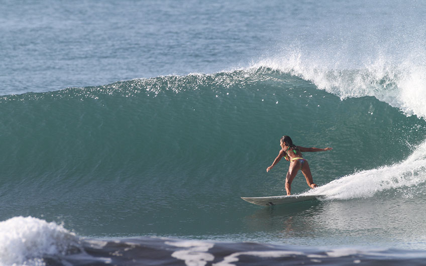 A surfer swings nimbly in the warm ocean waves at Tamarindo Beach.